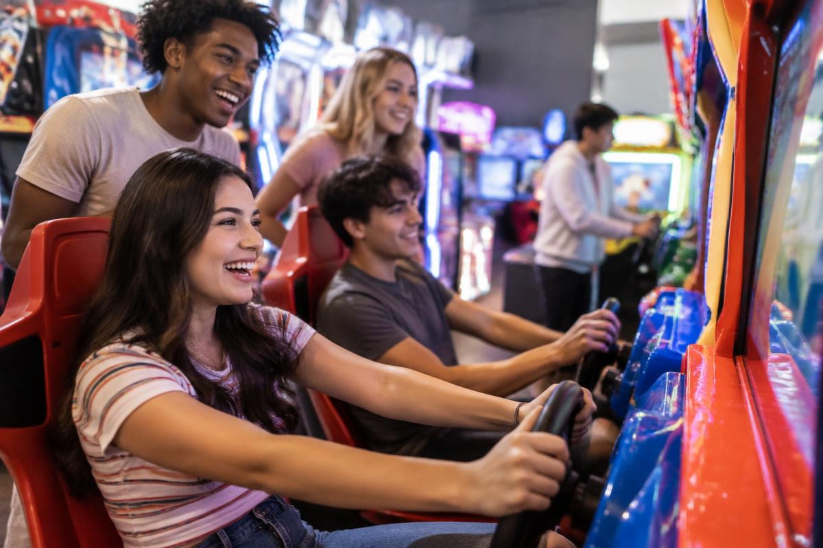 Illustrative lifestyle photograph of friends laughing while playing arcade games